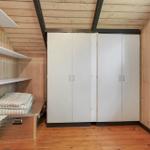 Schlafzimmer mit Holzwand, weißen Schränken und Regalen. Bettbox mit Bettwäsche.