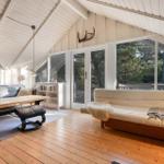 Wohnraum mit Holzboden, Sofa, Couchtisch und großen Fenstern zur Aussicht.