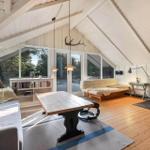 Wohnzimmer mit Holzboden, Kamin und großem Fensterblick.