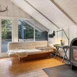 Wohnraum mit Sofa, Kamin und Fenster zur Außenterrasse.