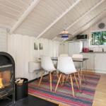 Küche mit Esstisch, Kaminofen und Fenster mit Blick auf Grün.