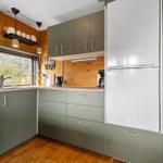 Küche mit grünen Schränken, Holzwand und Fenster