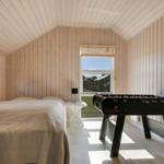 Schlafzimmer mit Bett, Tischfußball und Fenster zum Garten.