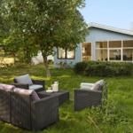 Garten mit Sitzgruppe vor einem blauen Haus mit großen Fenstern.