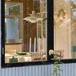 Fensterblick in ein Haus mit Tisch, Kerzen und Blumen. Hausnummer 234 an der Fassade.