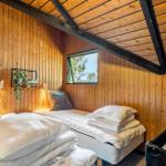 Zwei Betten in einem Holzhaus mit Dachschrägen und kleinem Fenster.