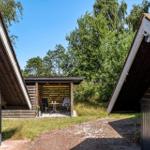 Zwei Holzhäuser mit Terrasse und Gartenbereich. Holzterrasse mit Tisch und Stühlen.