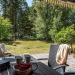 Terrasse mit Tisch, Stühlen und Blick auf Wald.