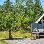 Holzterrasse mit Bank, Körben und Pflanzen vor einem Haus mit dunklem Holzverkleidung.