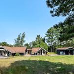Haus mit Terrasse, Garten und Bäumen unter blauem Himmel.