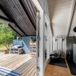 Terrasse mit Holzdecke und Grillplatz. Im Inneren steht ein Holzofen mit Feuer.