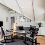 Wohnzimmer mit Sofa, zwei Sessel, Fernseher und Holzboden.