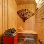 Sauna mit Holzwand, Sitzbank, Badeeimer und dekorativem Fächer.