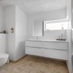 Badezimmer mit Waschmaschine und Trockner, Spiegelschrank und Toilette.