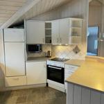 Küche mit weißen Schränken, Kühlschrank, Mikrowelle und Herd.