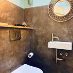 Bathroom with toilet, sink, and round mirror on the wall.