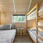 Room with wooden walls, bunk bed, and window with view of trees.