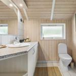 Bathroom with sink, toilet, and window. Wooden walls and floor tiles.