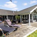 Deck with loungers, table and chairs. House with roof and glass front.