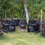Fire pit with seating in the garden. Surrounded by trees and hedges.