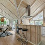 Kitchen with dining area, wood walls and ceiling, bar stools, and windows to the outside.