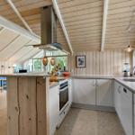 Kitchen with wooden ceiling, white cabinets, and kitchen island. Living area with blue sofa in background.