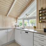 Kitchen with wooden walls, window, sink, and dish rack.
