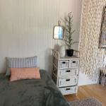 Ein Bett mit Kissen und einem Korbregal an der Wand.