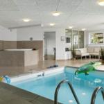 Indoorpool mit Whirlpool und Sitzbereich. Grünliches Krokodil auf dem Wasser.