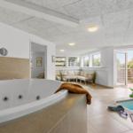 Whirlpool und Pool im Innenbereich mit Sitzgelegenheit und Fenster