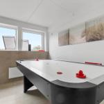 Ein Raum mit Airhockey-Tisch, Fenstern und Strandbildern an der Wand.