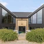 Moderne Villa mit Pool und großzügigen Fenstern. Holzstufen und grüne Hecken.