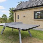 Tischtennisplatte im Garten vor einem Haus mit Backsteinwand und Dach.