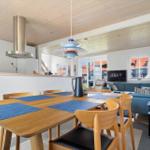 Essbereich mit Holztisch und Stühlen, blauen Tischdecken und Wohnzimmer im Hintergrund.