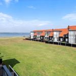 Ausblick auf Grünfläche, Wasser und moderne Häuser mit roten Dächern.