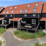 Schwarze Häuser mit roten Dächern und Terrassen im Freien.