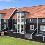 Schwarze Holzhäuser mit roten Dächern und Terrassen mit Gartenmöbeln.