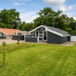 Modernes Ferienhaus mit Garten und Terrasse. Hintergrund: Bäume und klarer Himmel.