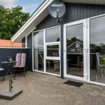 Terrasse mit zwei Stühlen und Tisch vor einem Haus mit Glasfront.
