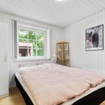 Schlafzimmer mit Bett, Kleiderschrank und Fenster. Wandbild und Holzregal sind sichtbar.