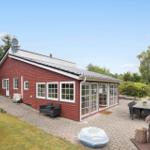 Rotes Haus mit Glasveranda, Terrasse und Garten. Außentisch, Sitzgelegenheiten und Whirlpool.