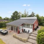 Rotes Haus mit Terrasse, Grill und Garten. Große Glasfront zur Außenterrasse.