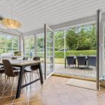 Essbereich mit Tisch und Stühlen, große Glastüren zu Terrasse mit Garten.