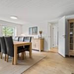 Esszimmer mit Holztisch, schwarzen Stühlen und Glasvitrine.