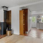 Wohnbereich mit Kaminofen und Küche mit Fenstern.