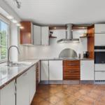 Küche mit Arbeitsfläche, Herd, Dunstabzug und Fenster.