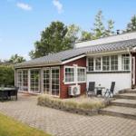 Roter Holzhaus mit Terrasse und Gartenbereich mit Sitzgelegenheiten.