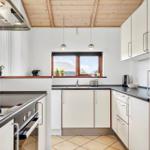 Küche mit weißen Schränken, dunklem Arbeitsplatz und Holzdecke.
