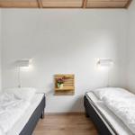 Zwei Einzelbetten mit weißen Bettwäsche stehen in einem Raum mit Holzdecke und Wandbeleuchtung.