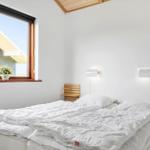 Schlafzimmer mit Doppelbett, Fenster und Wandlampen.